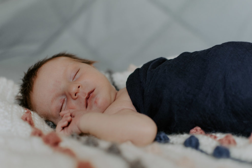 Sleepy newborn in blue wrap