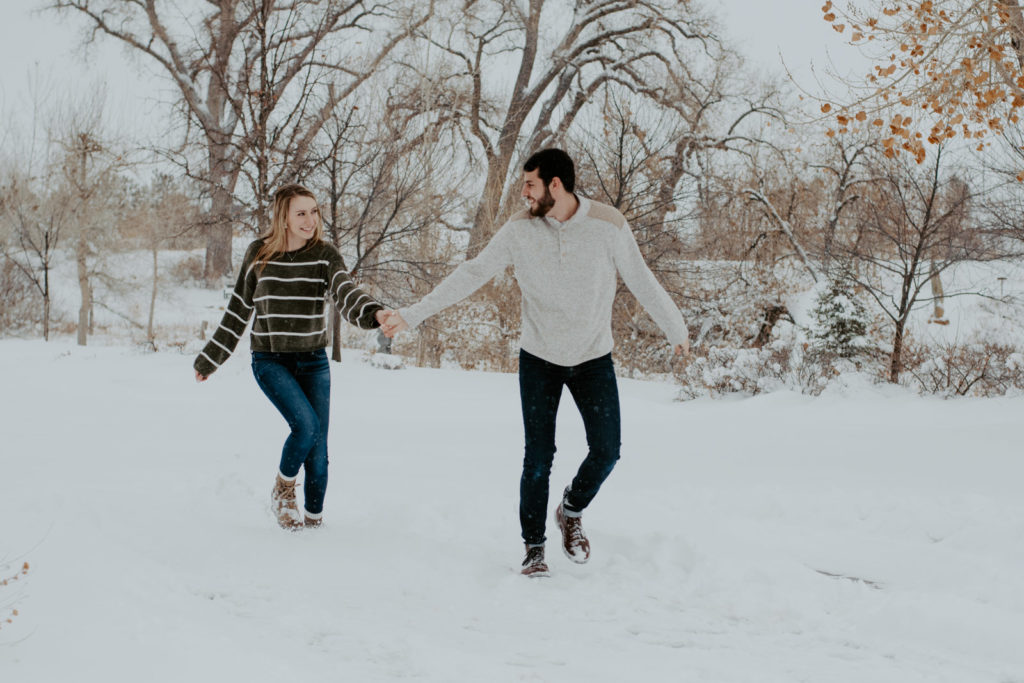 Couple running together in snowy Loveland, CO