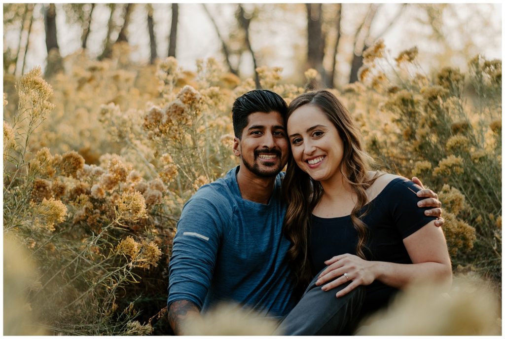 Happily engaged couple smiles during fall engagement photo session in Fort Collins