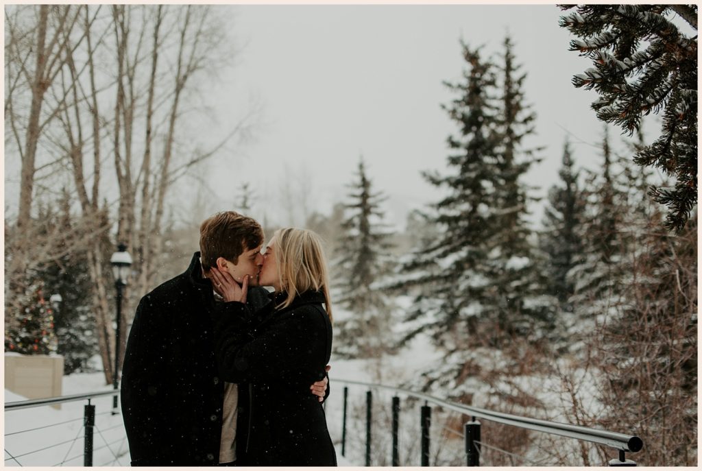 Couple kisses during their winter mountain proposal