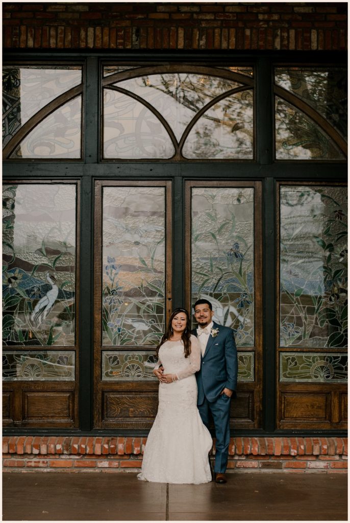 Couple stand in front of stained glass window at Lionsgate Event Center