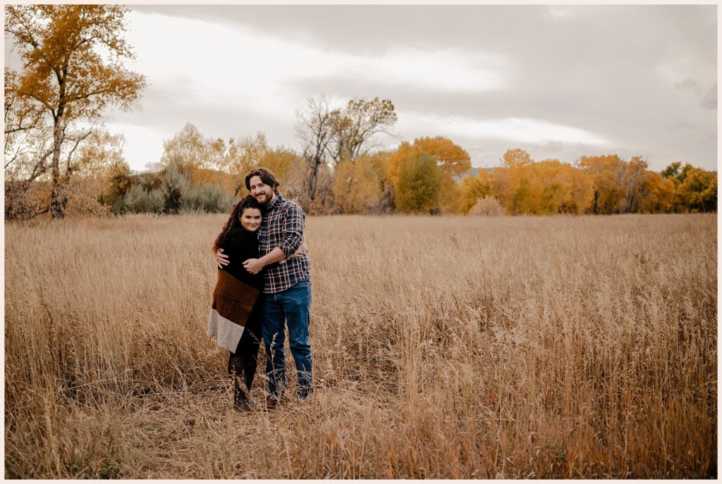 Couple hugs in a field during their fall engagement photos in Colorado