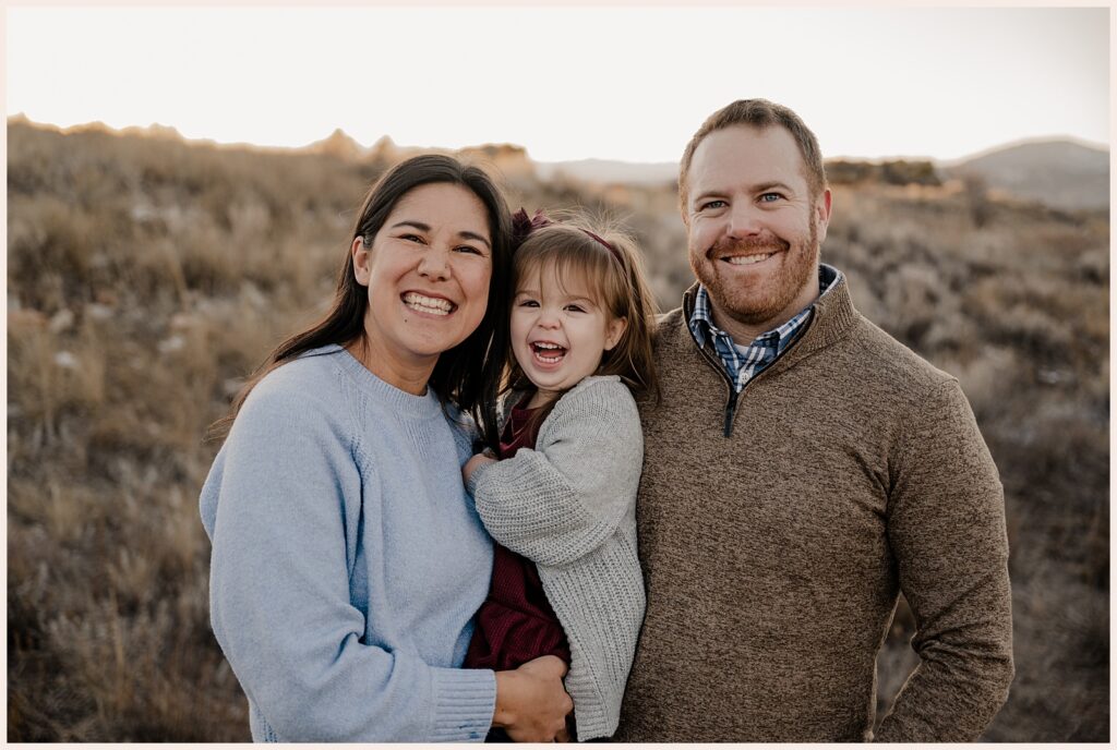 Family of three smiles at their Northern Colorado Family Photographer