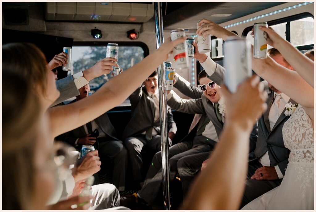Wedding party raise a glass in a party bus on their way to the Brookside Gardens wedding 