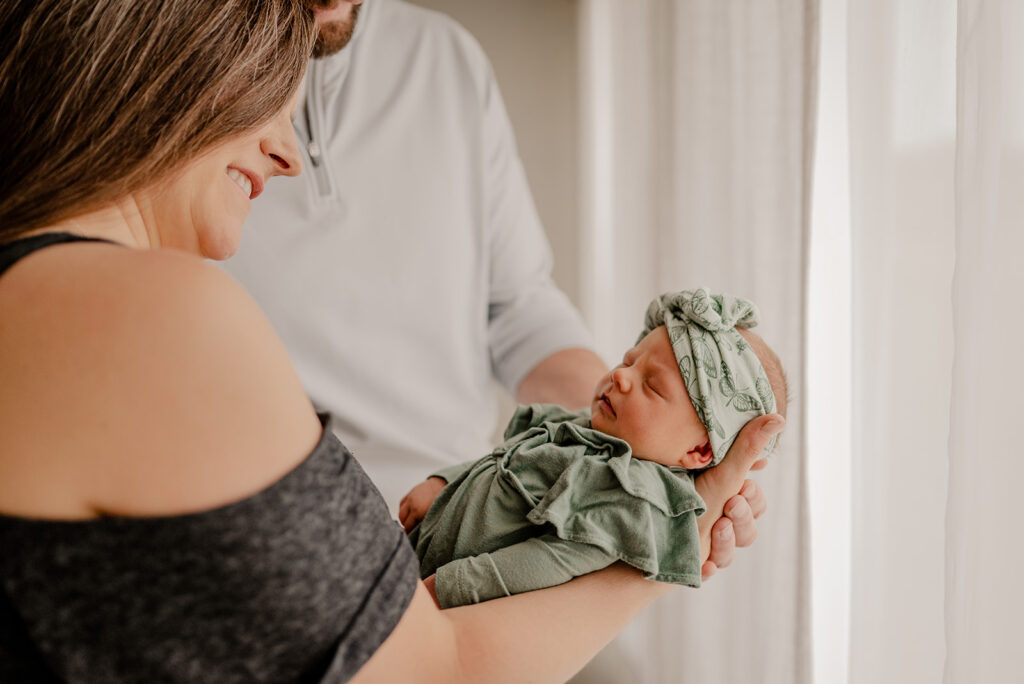 Baby girl sleeping in parents arms during her newborn photos in Northern Colorado